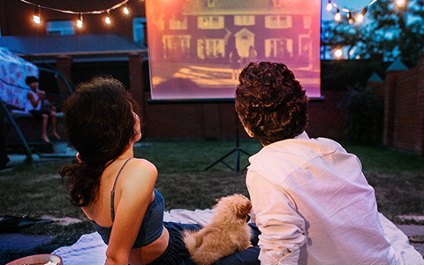 outdoor movie, backyard cinema, projector screen, couple watching, dog companion